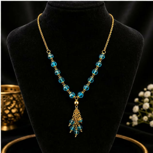 A gold chain necklace with blue faceted beads and a tassel pendant displayed on a black bust.