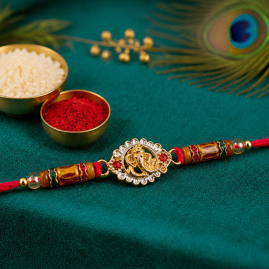 Close-up of Ganesha silver ring devotional rakhi with red and green beads.