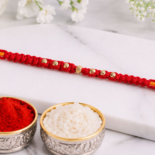 Close-up of minimal red stone rakhi with fine beads and festive thread.