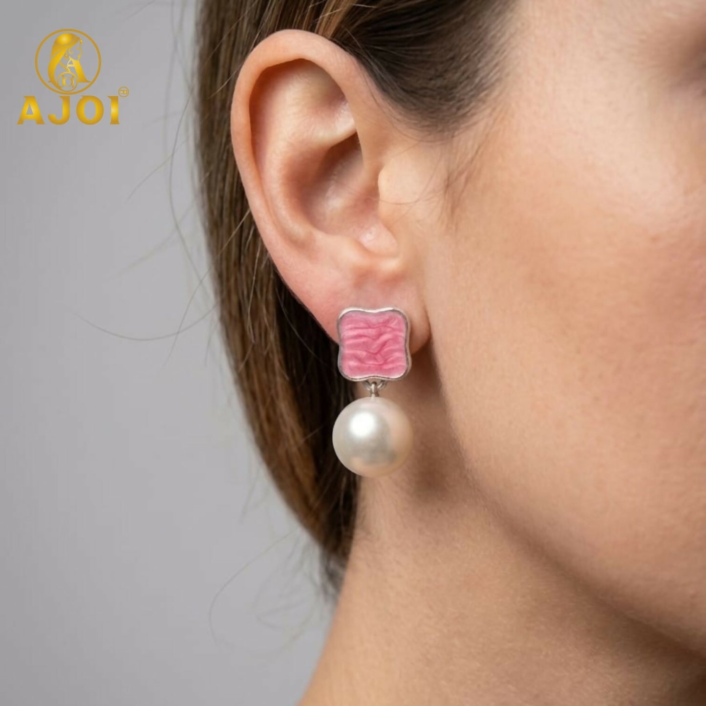 Close-up of pearl drop earrings showing vibrant enamel stud details