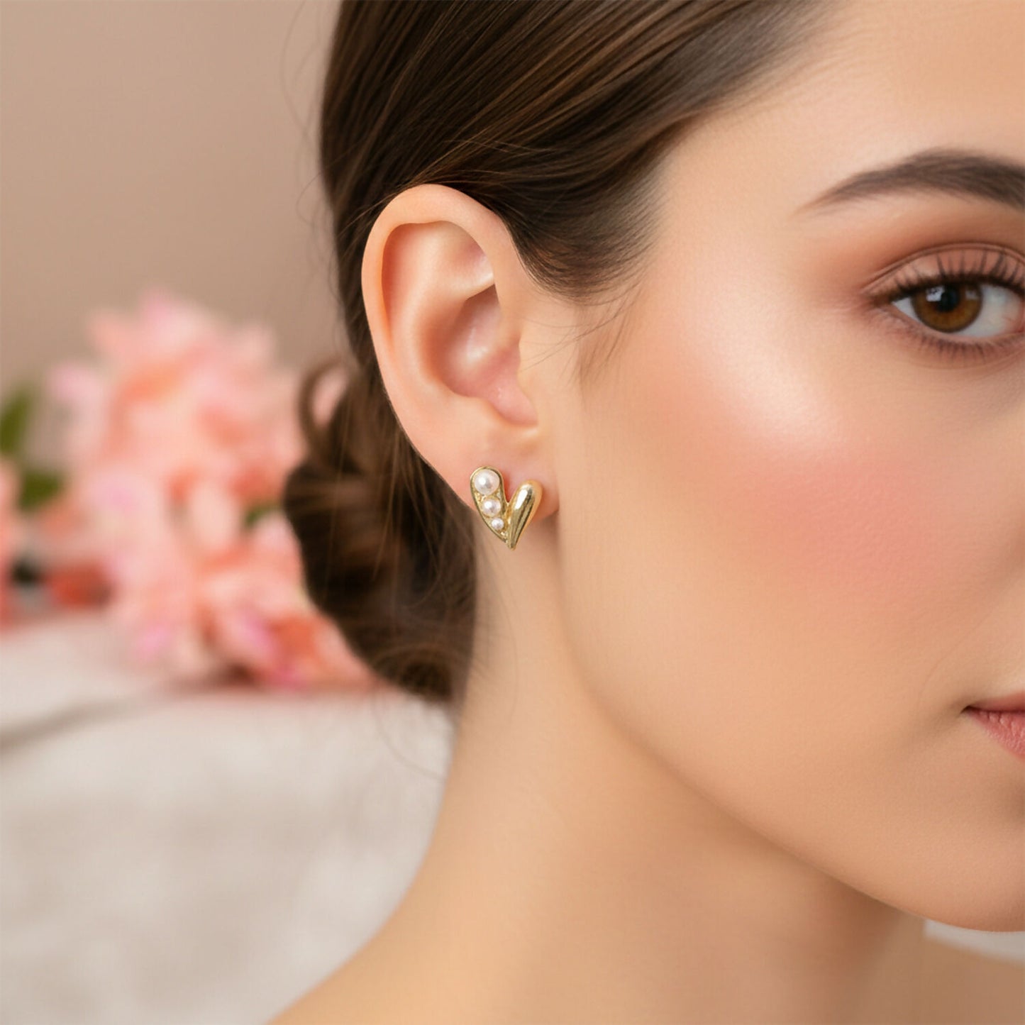 Gold pearl heart stud earring worn on ear