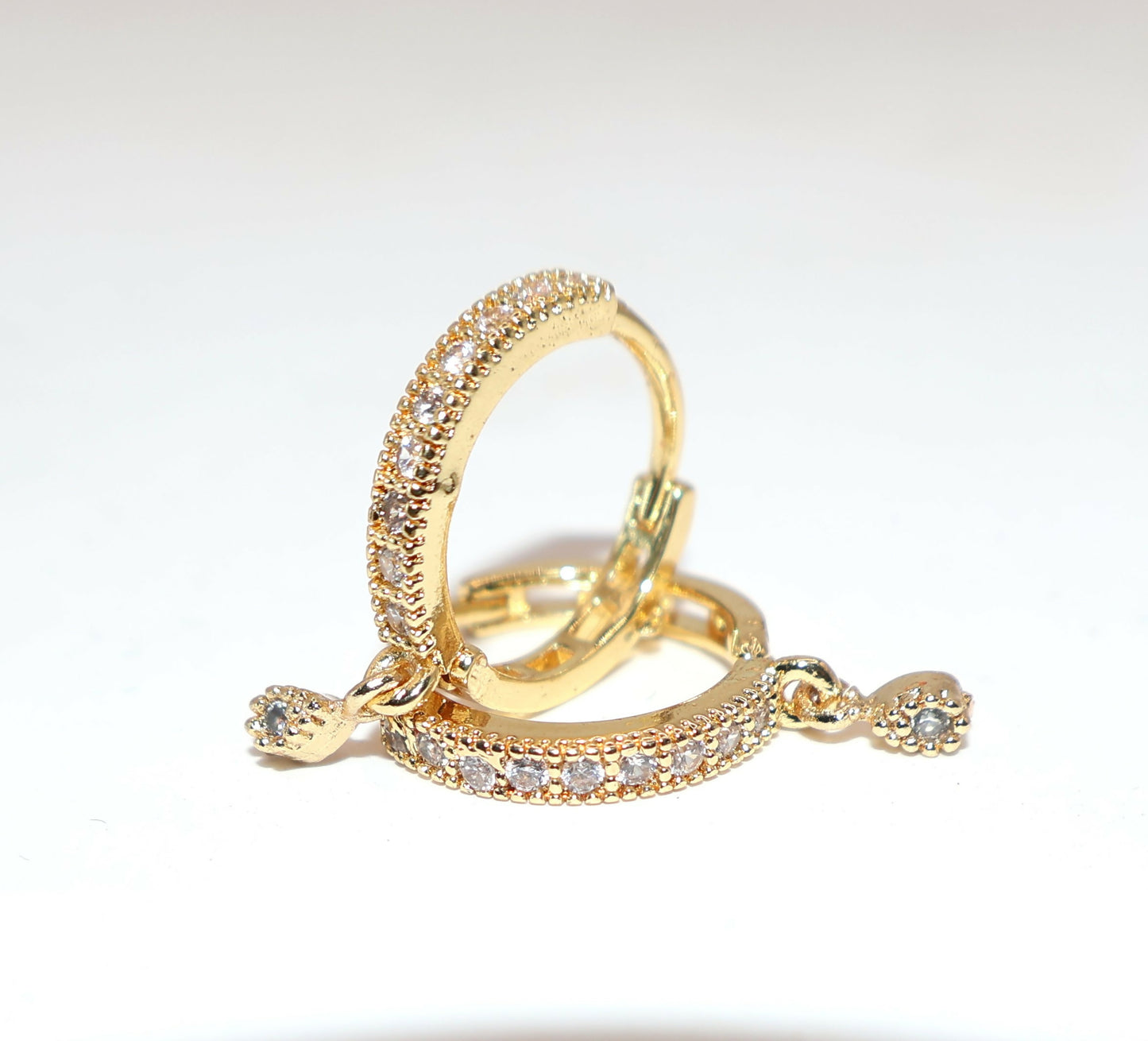 Side angle of lightweight gold plated Bali geometric floral dangle huggie earrings