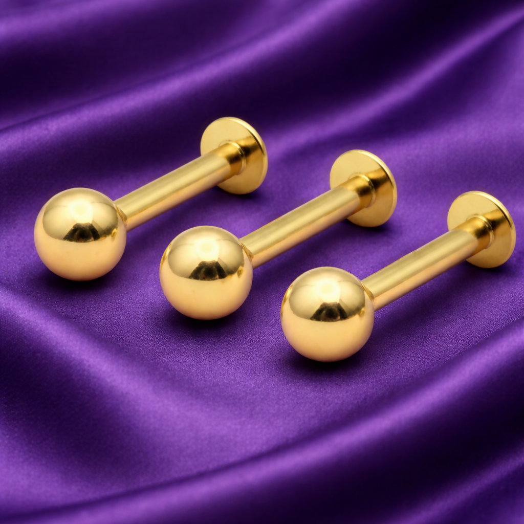Close-up of gold-plated tiny ball flat back labret stud earrings highlighting smooth surface