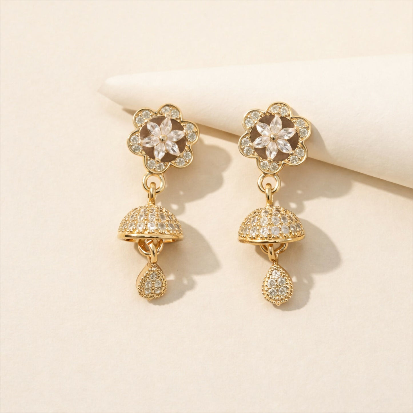 Close-up of rose gold drop earrings featuring geometric studs and starburst crystal charm