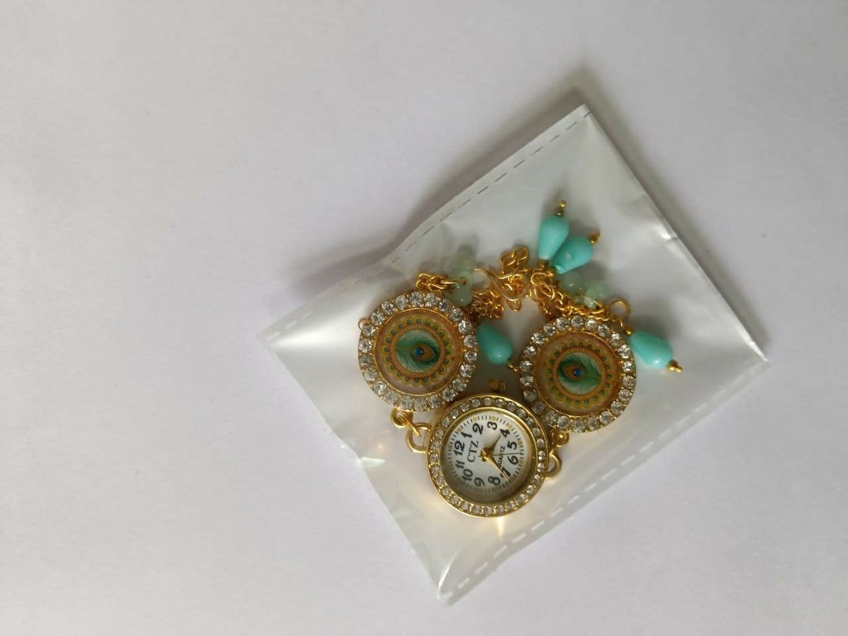 Gold tone bracelet watch with peacock eye design and turquoise beads in a clear plastic bag on a white background.