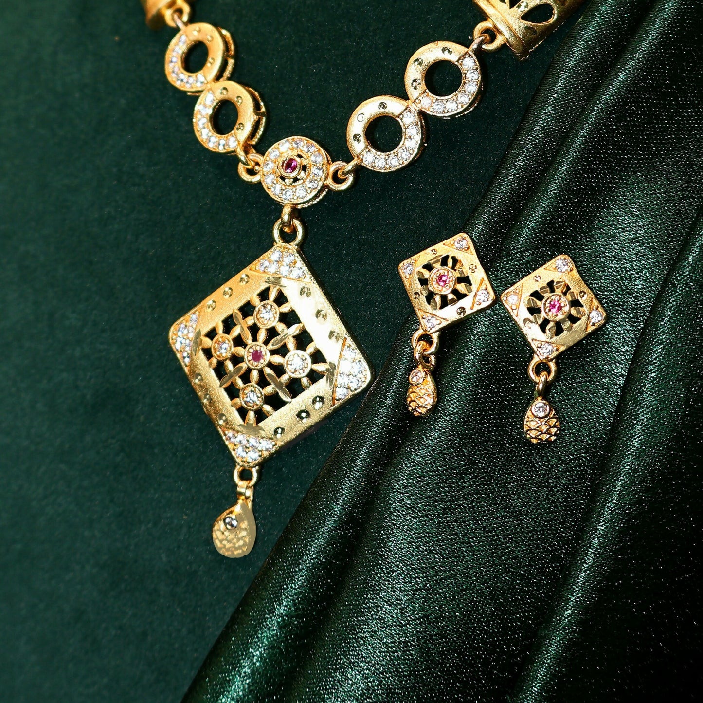 Detailed view of gold plated square pendant featuring CZ and ruby-toned accents