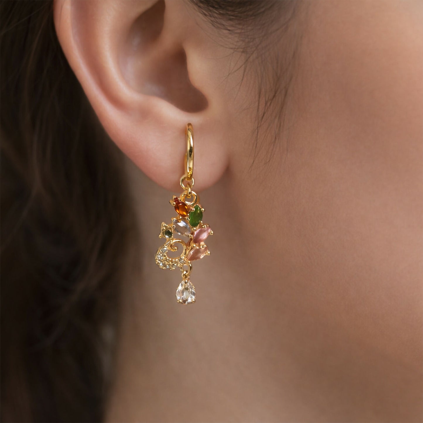 Close-up of multicolor gemstone leaf motif drop earrings with crystal accents