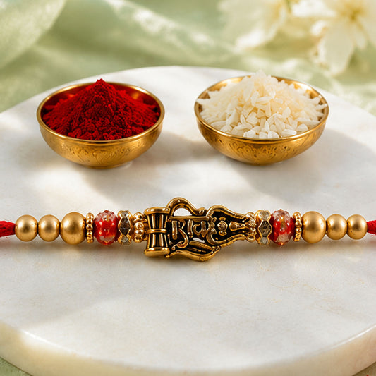 Close-up of Shiv Trishul Damru Rakhi with engraved Shiv word on a golden plate.