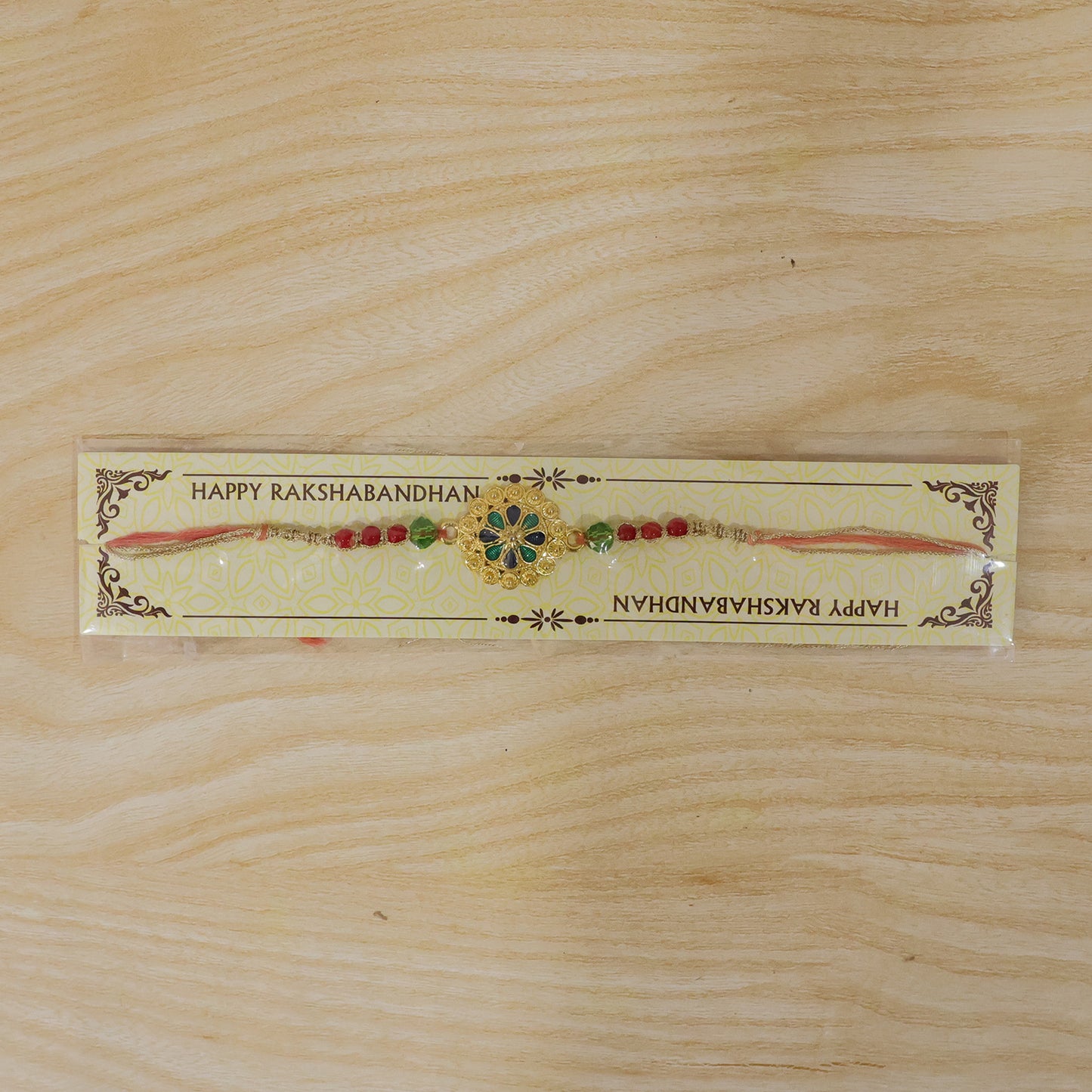 Gold Blue Flower Rakhi with Green Beads and Red Pearl Accents