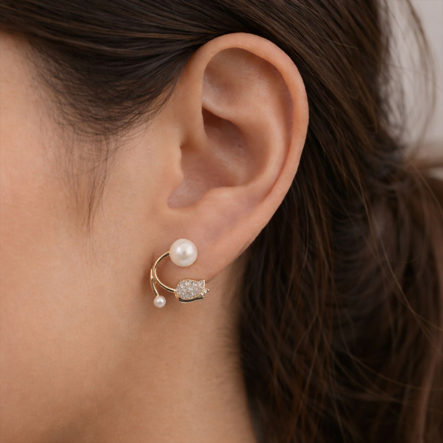 Close-up of curved pearl and stone charm on earrings