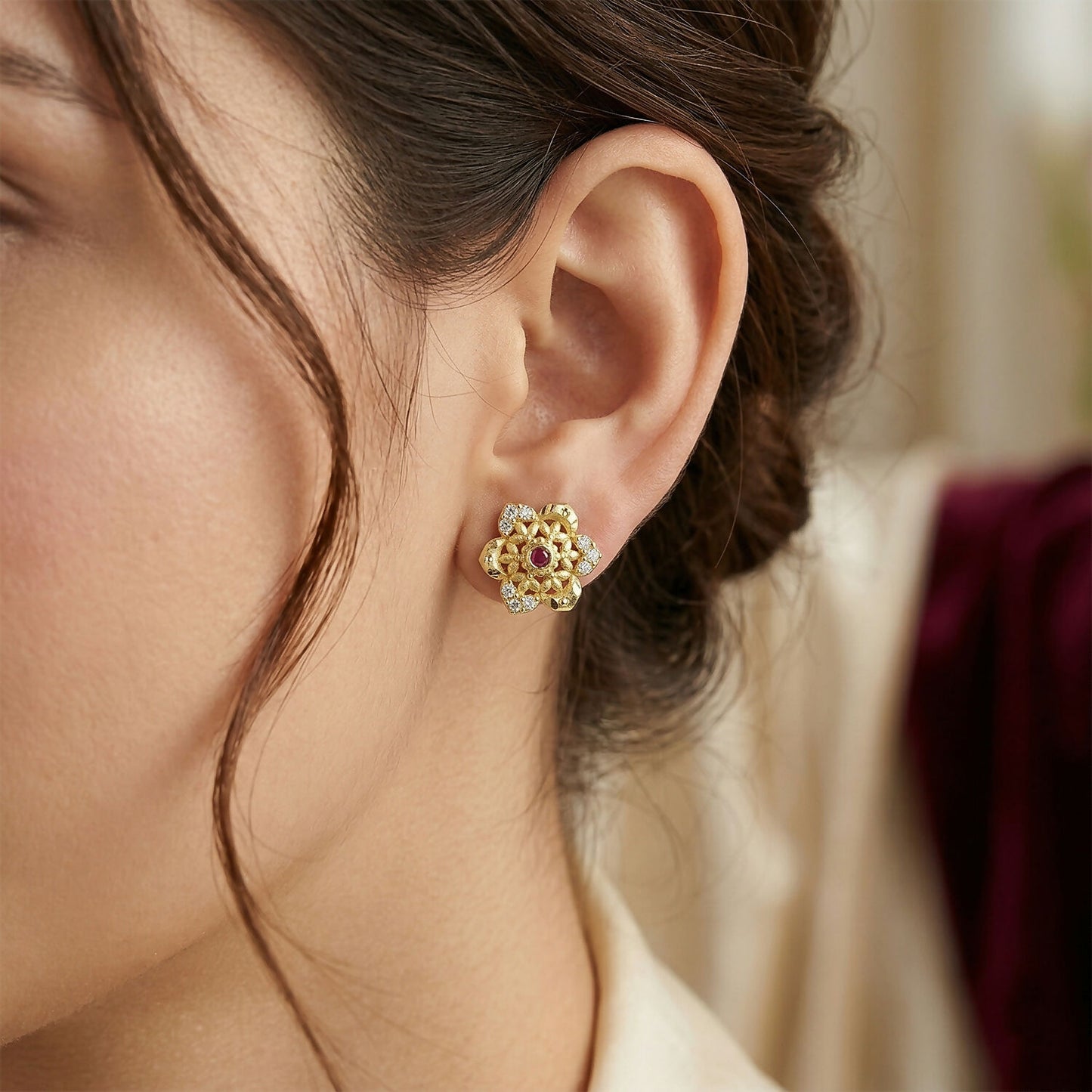Intricate floral pattern on gold stud earrings with center stone