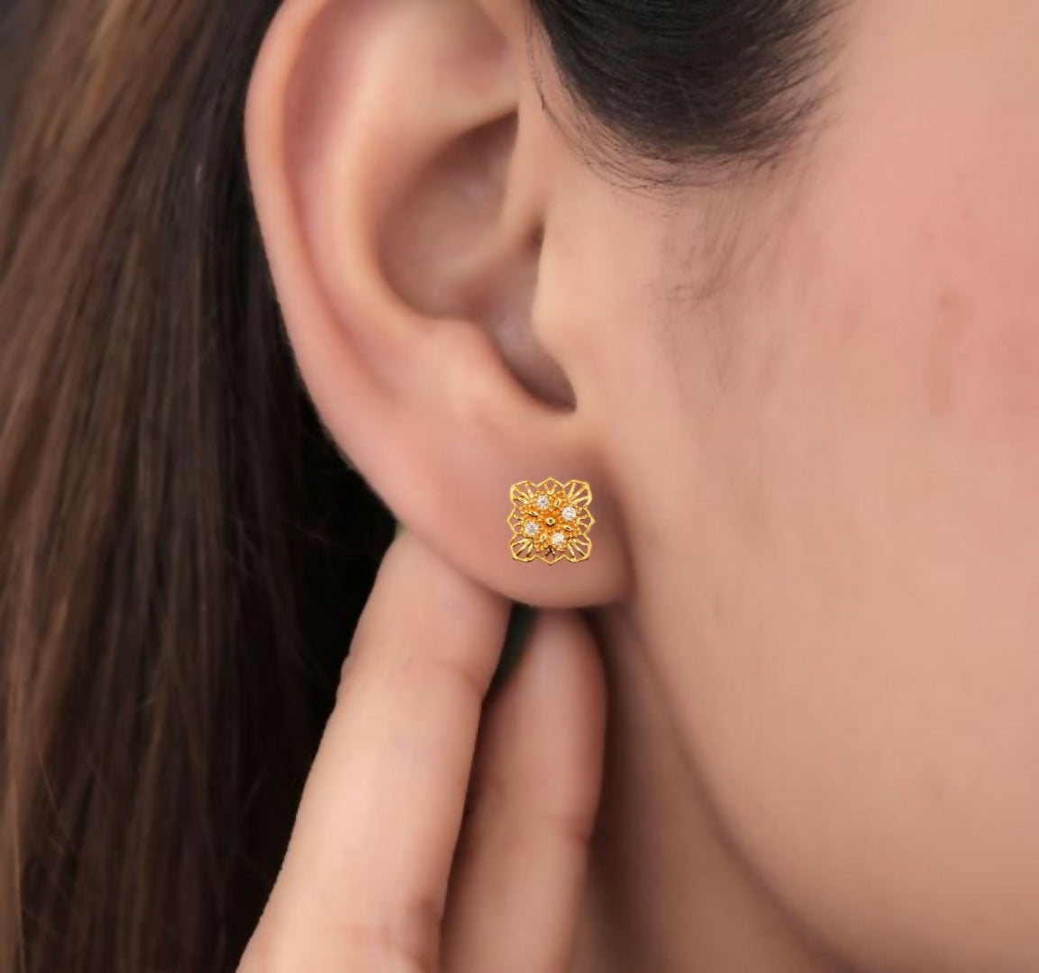 Top view of gold plated floral square stud earrings highlighting delicate filigree patterns