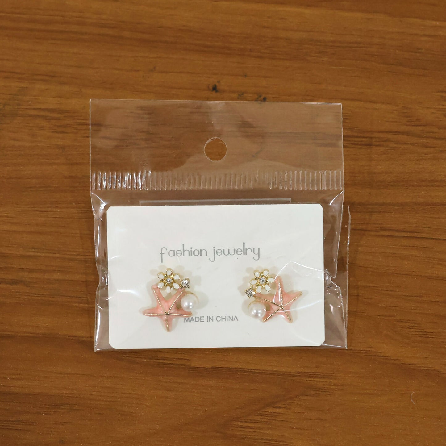 Pink starfish pearl earrings styled on model ear