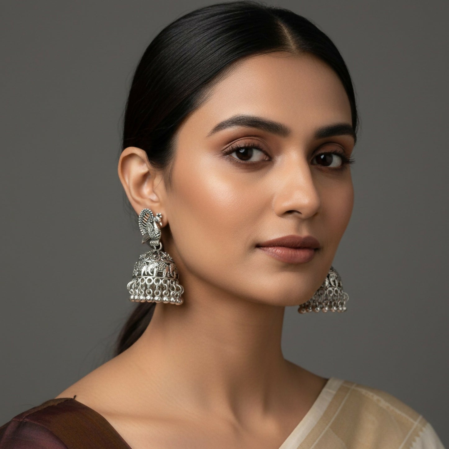 Close-up of oxidised silver peacock jhumka earrings showing intricate ghungroo hanging
