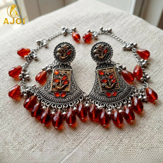 Oxidised two-tone floral earring with ruby red crystal drop, front view