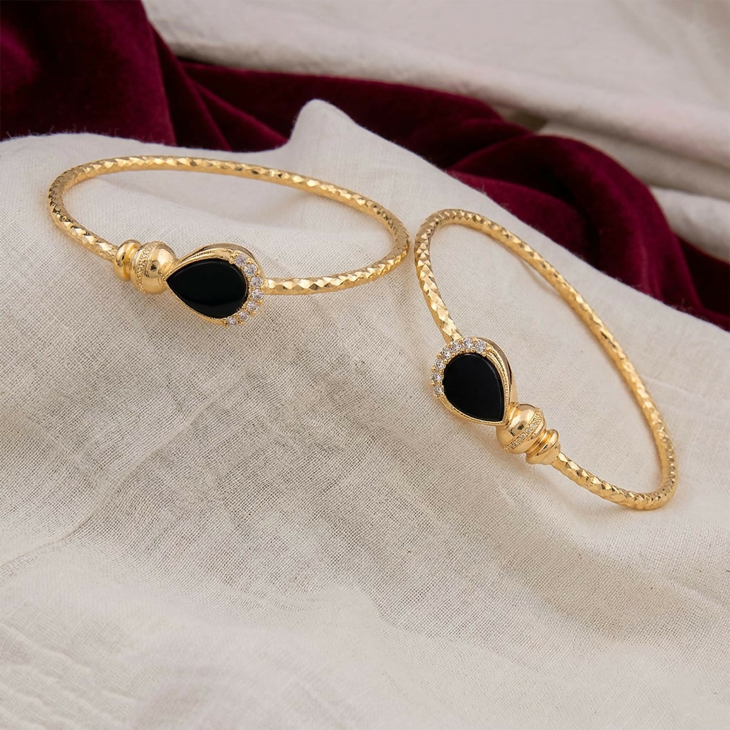 Side view of gold plated black stone kada bracelet pair