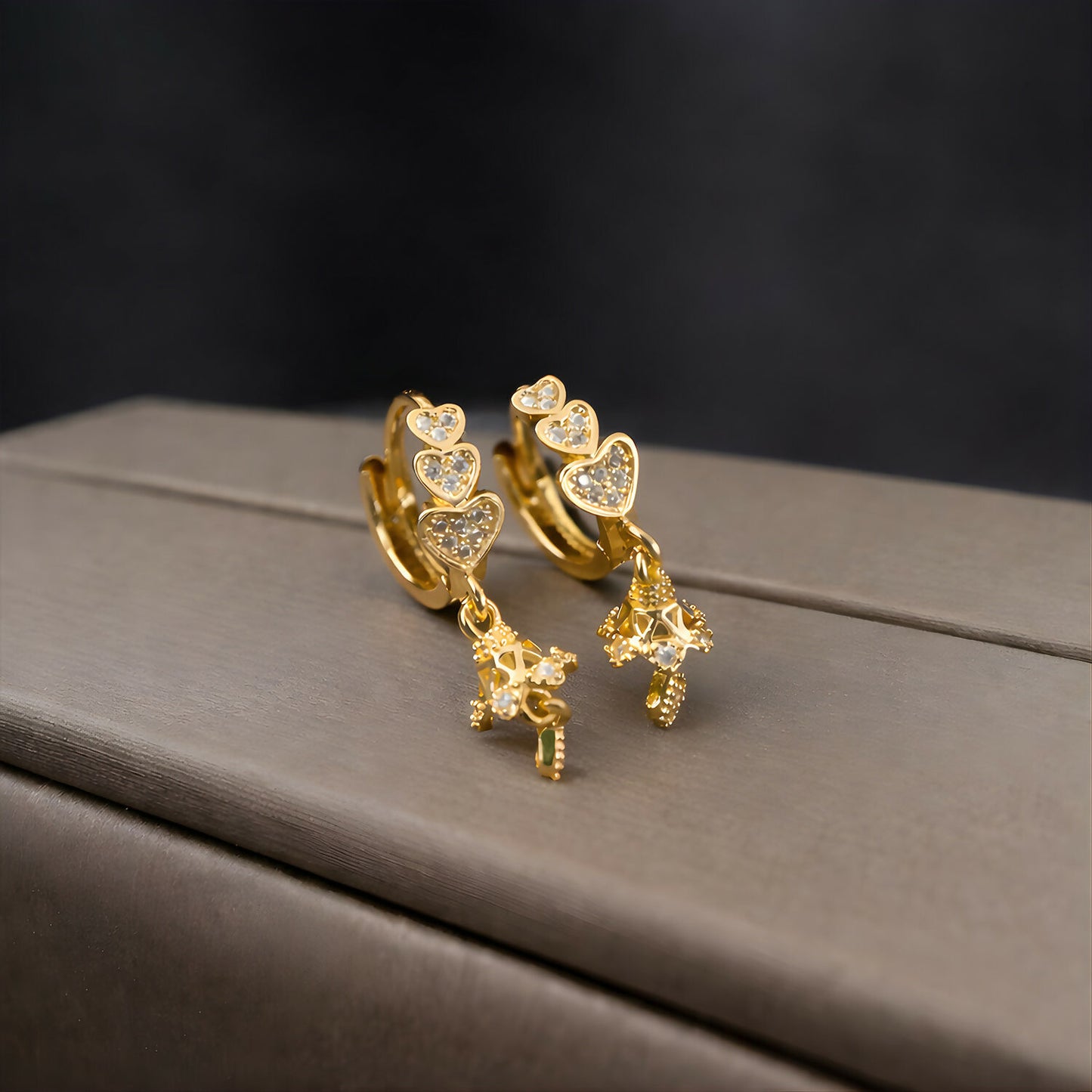 Side angle of lightweight triple heart drop earrings with charming stone details
