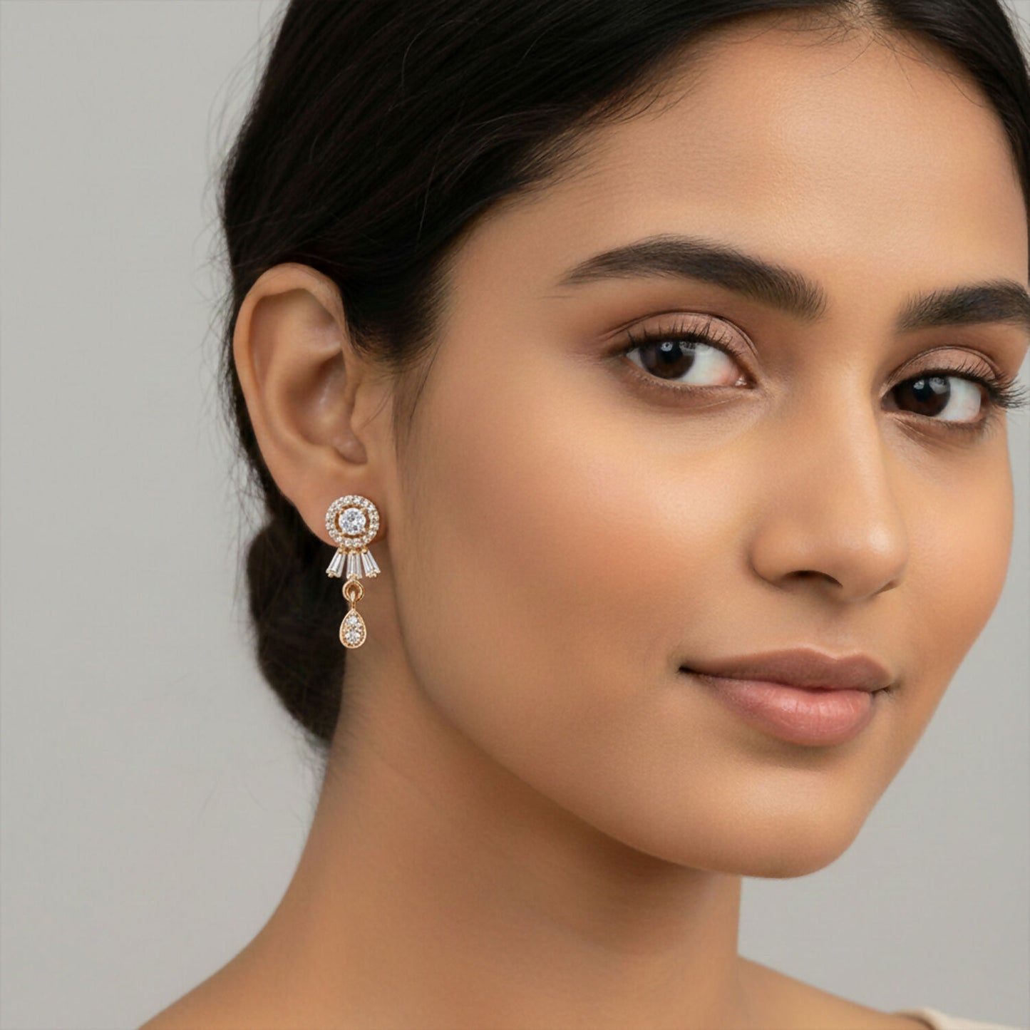 Close-up of gold plated cubic zirconia stud earrings with hanging drop design