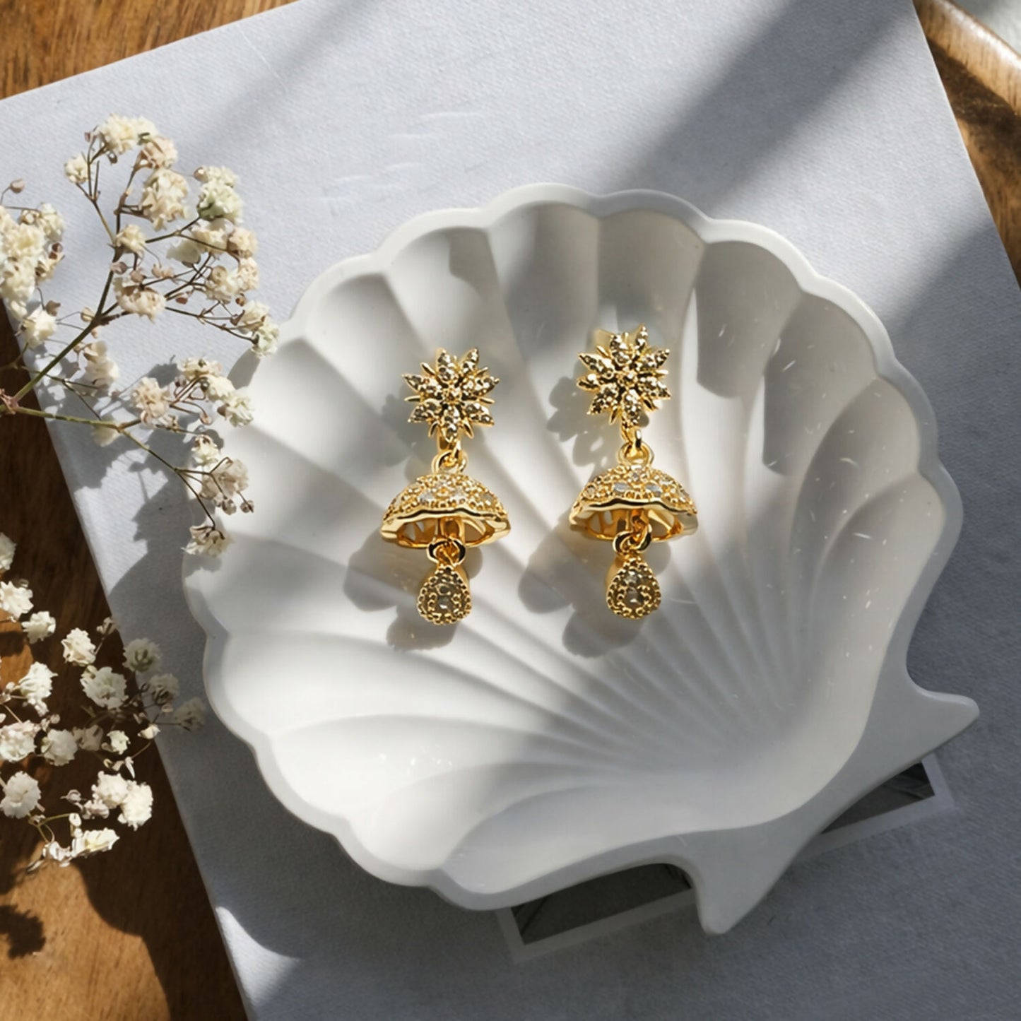 Close-up of sunburst floral jhumka earrings in gold finish with crystal accents
