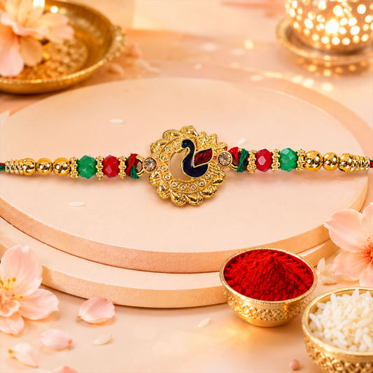 Close-up of peacock floral golden rakhi with blue green enamel and red beads.