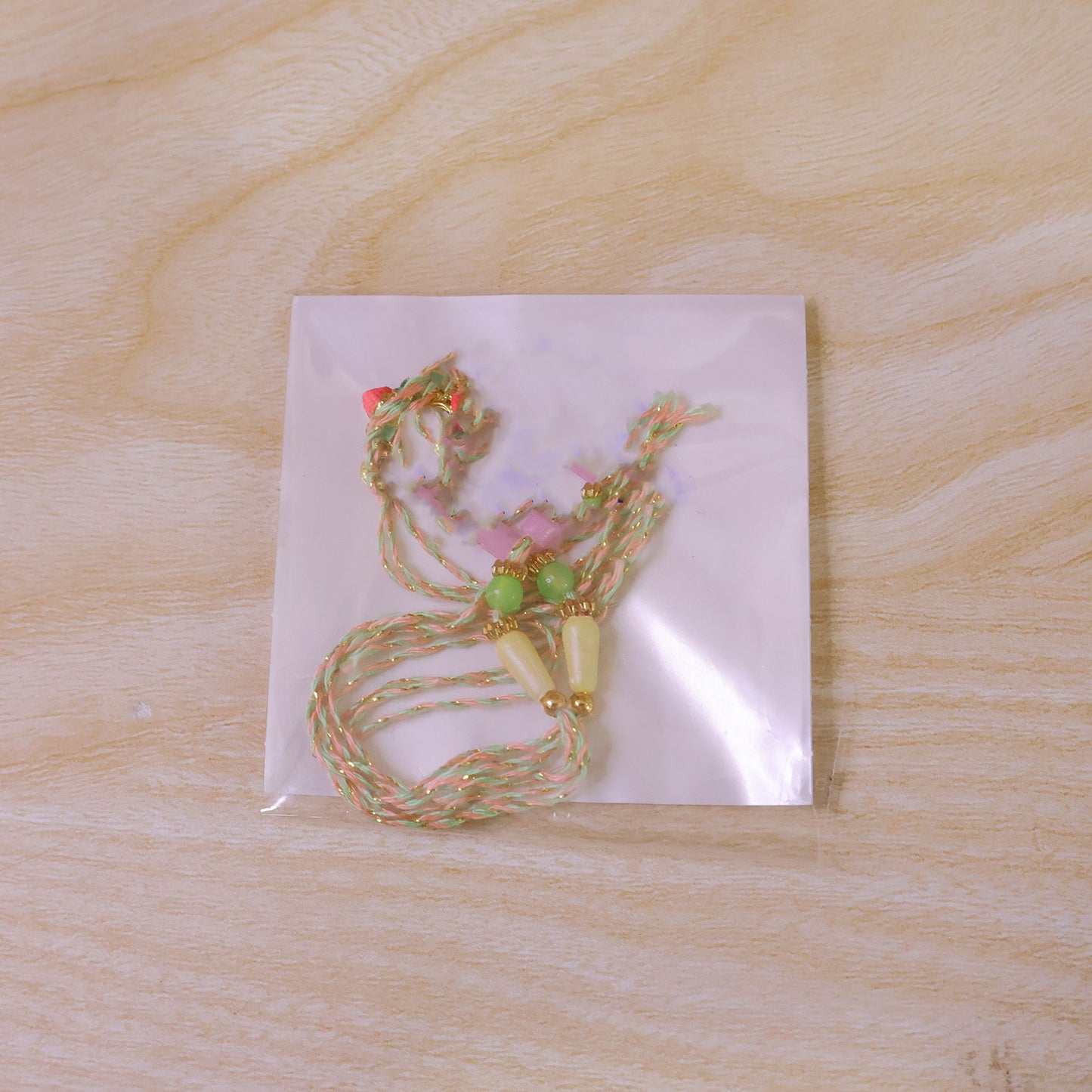 Gold Ganesha Charm Rakhi with Coral and Green Accents