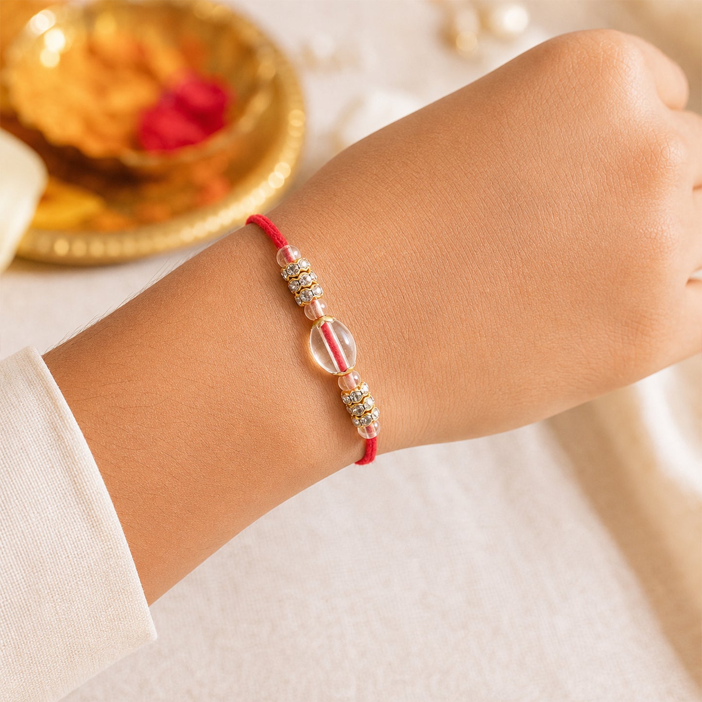 Red Thread Rakhi with Oval Crystal Bead Pendant and Golden Finish
