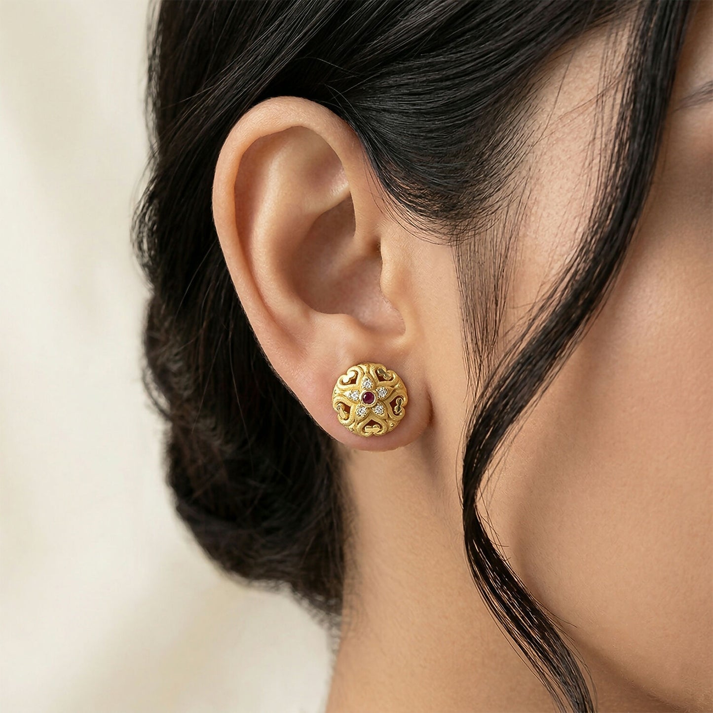Elegant gold stud earrings featuring intricate floral design and attached stones