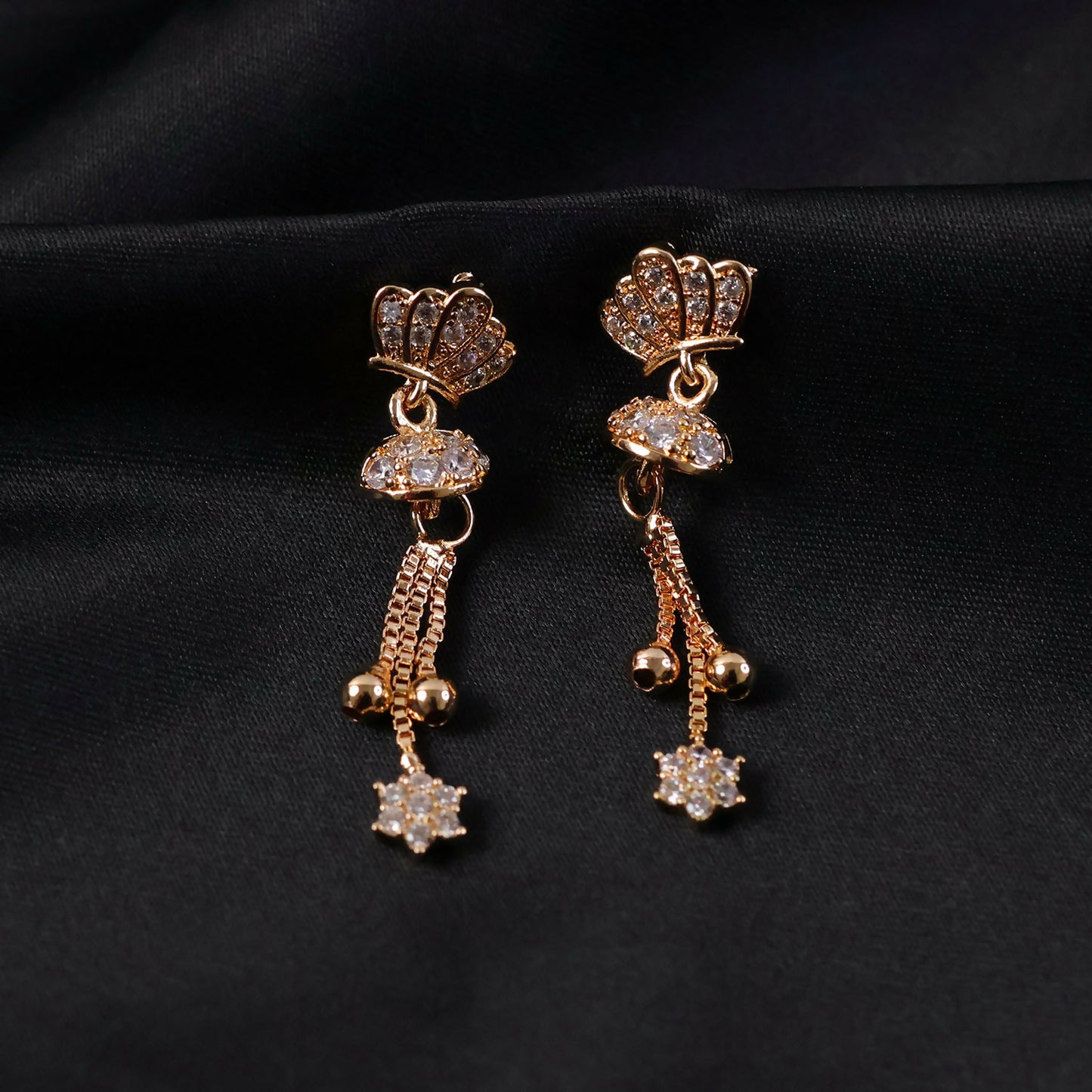 Detailed look at the crystal-embellished crown design on gold finish drop earrings