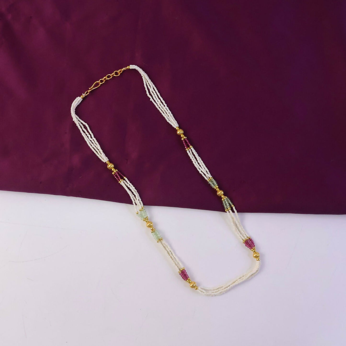 Close-up of pearl and colored beads with gold detailing on mala necklace