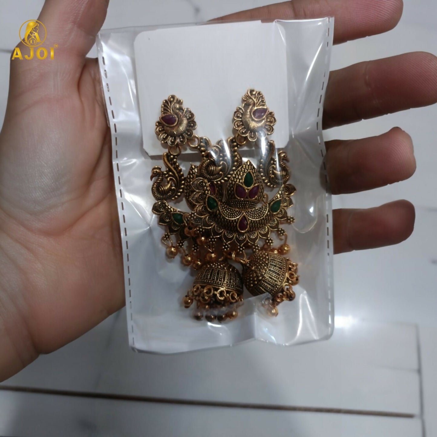 Back view of gold plated peacock jhumka earrings with detailed craftsmanship