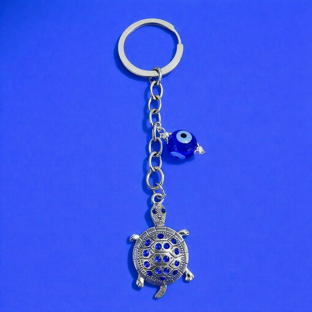 Close-up of turtle keychain with decorative evil eye pendant