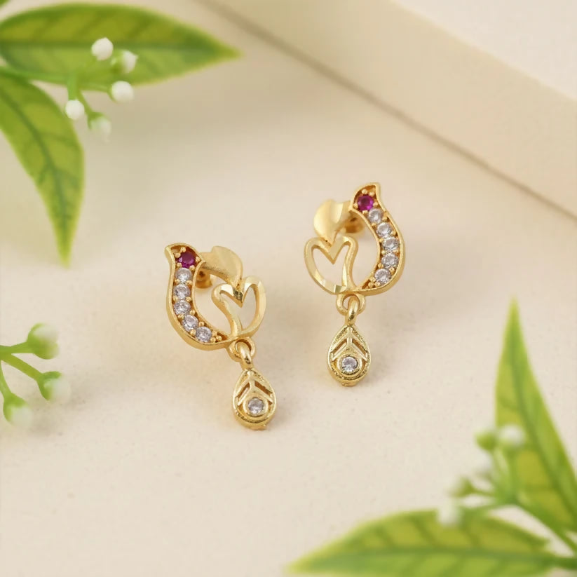 Close-up of gold heart drop earrings showing ruby and crystal details