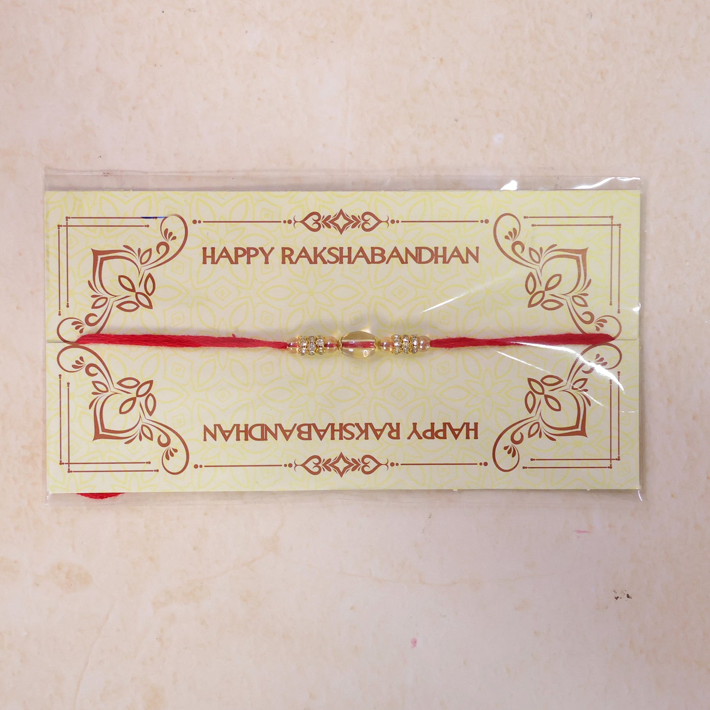 Red Thread Rakhi with Oval Crystal Bead Pendant and Golden Finish