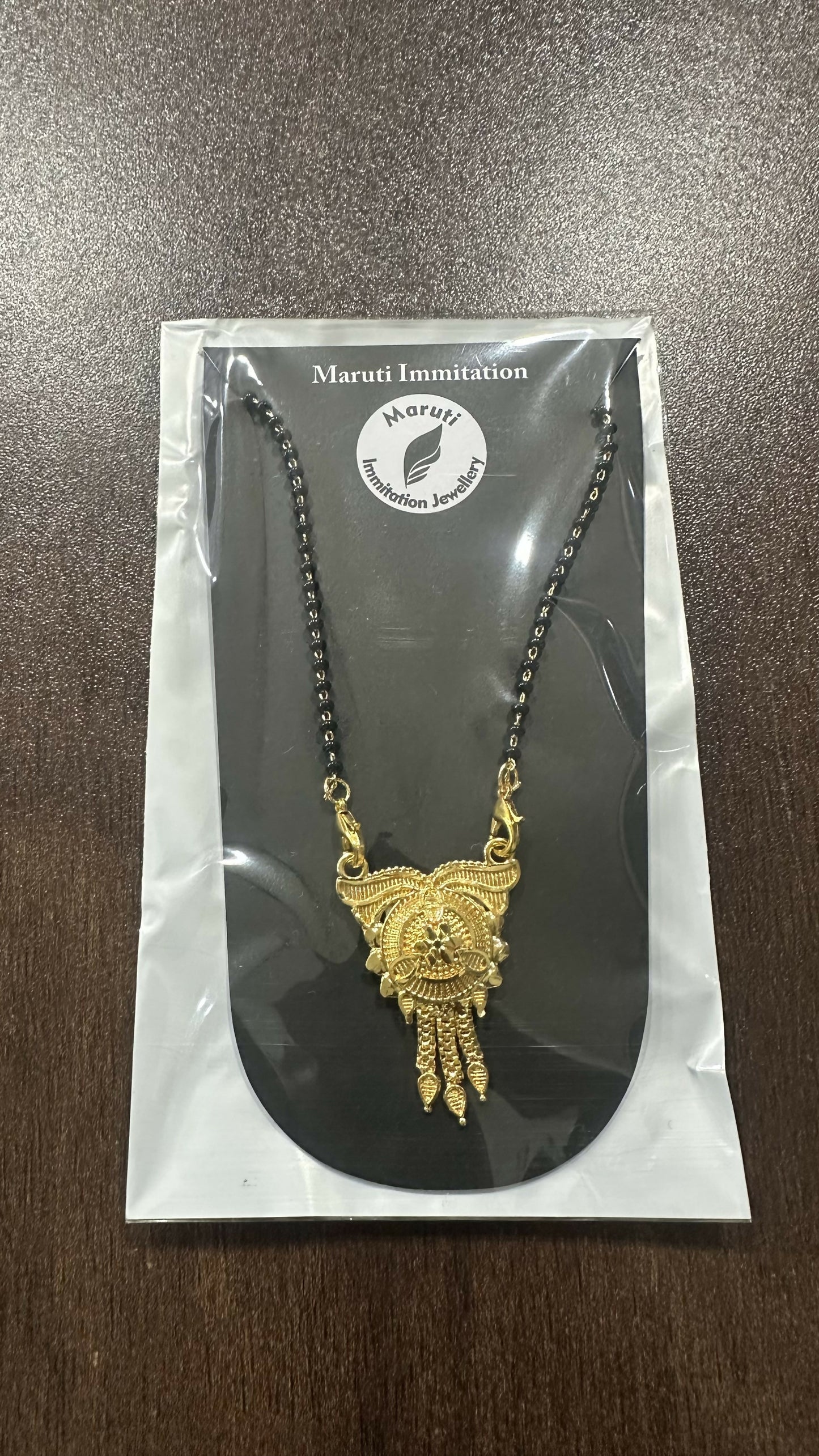 This stunning pendant, made of durable imitation metal and finished in gold tone, features detailed craftsmanship and a regal tassel drop.