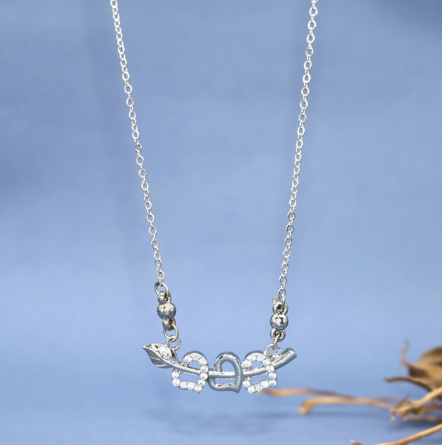 Close-up of silver tone double heart pendant pierced by Cupid's arrow with sparkling CZ stones