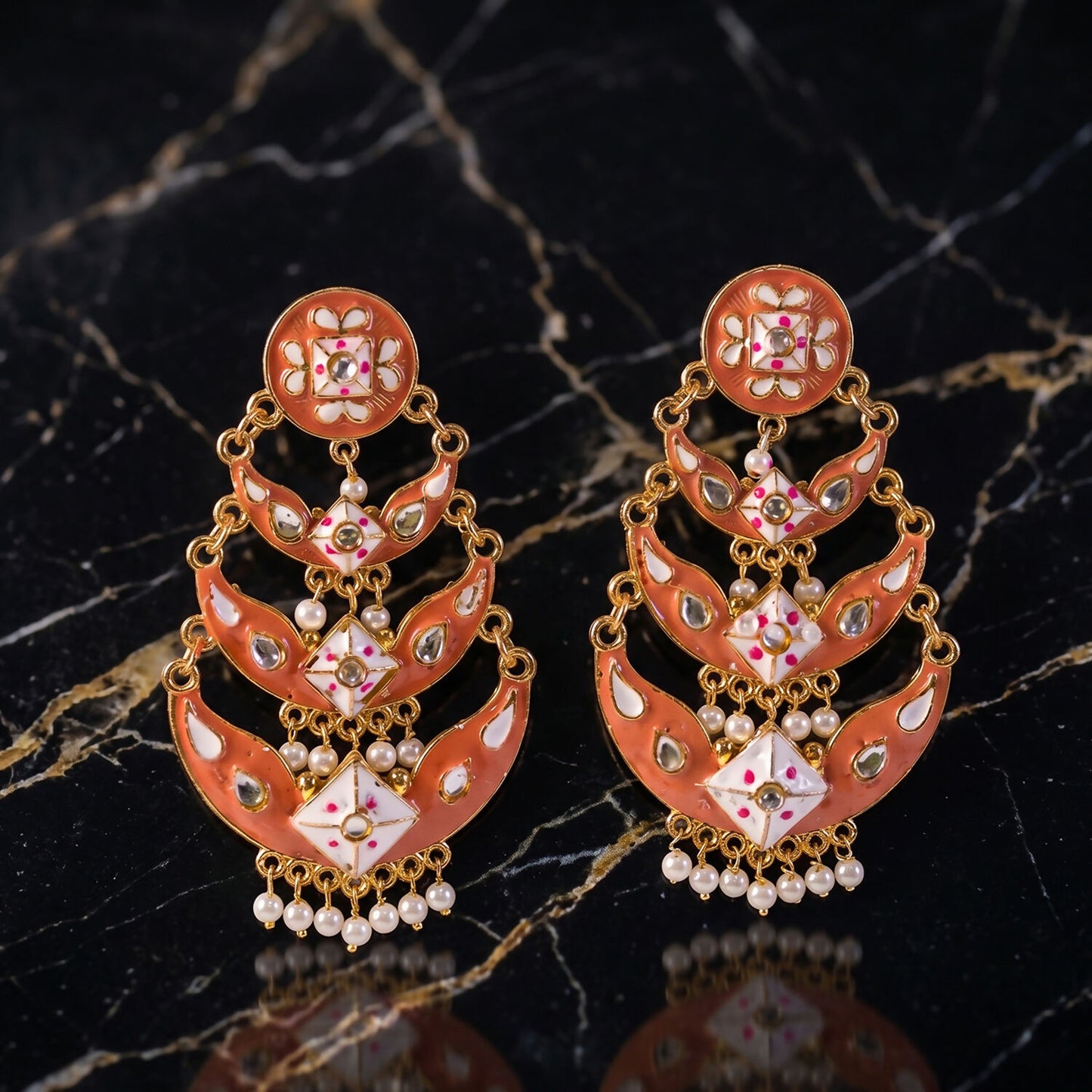 Close-up of detailed meenakari work and pearl accents on peach gold earring