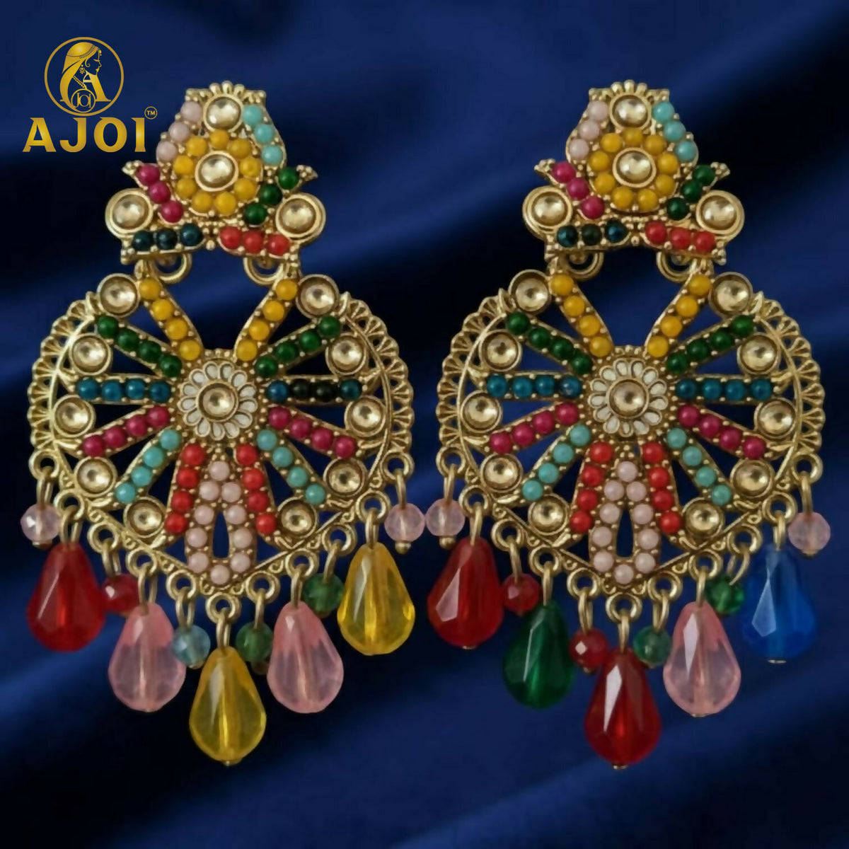 A pair of ornate gold earrings with multicolored beads and teardrop accents on a dark blue background.