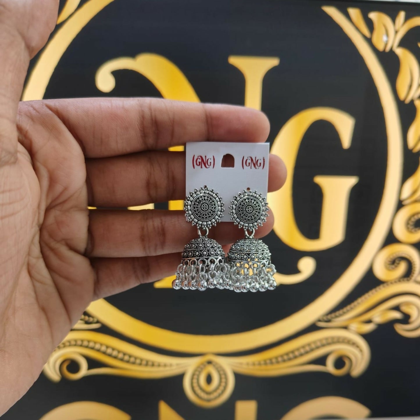 A pair of oxidised silver jhumka earrings displayed on a clean white surface.