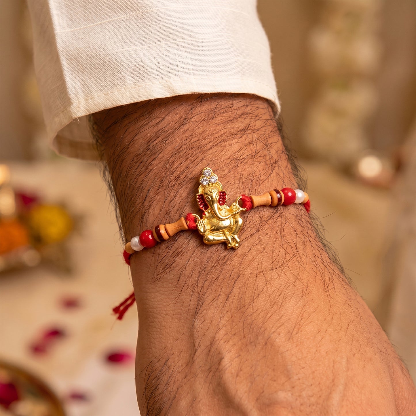 Golden Ganesha Rakhi with Peach Beads and Pearl Accents