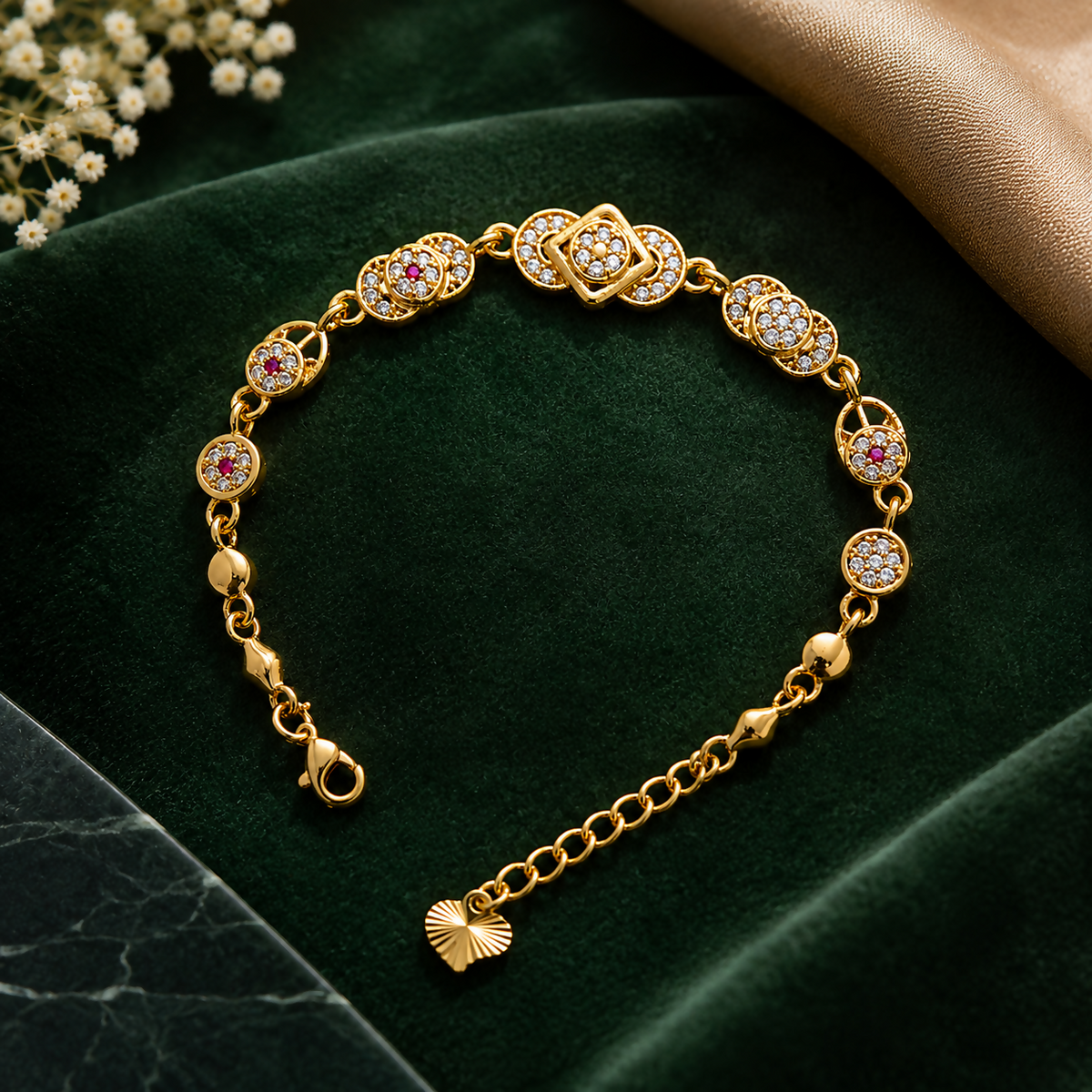 A gold-plated bracelet with alternating clear and red cubic zirconia stones, displayed on a dark green velvet background.