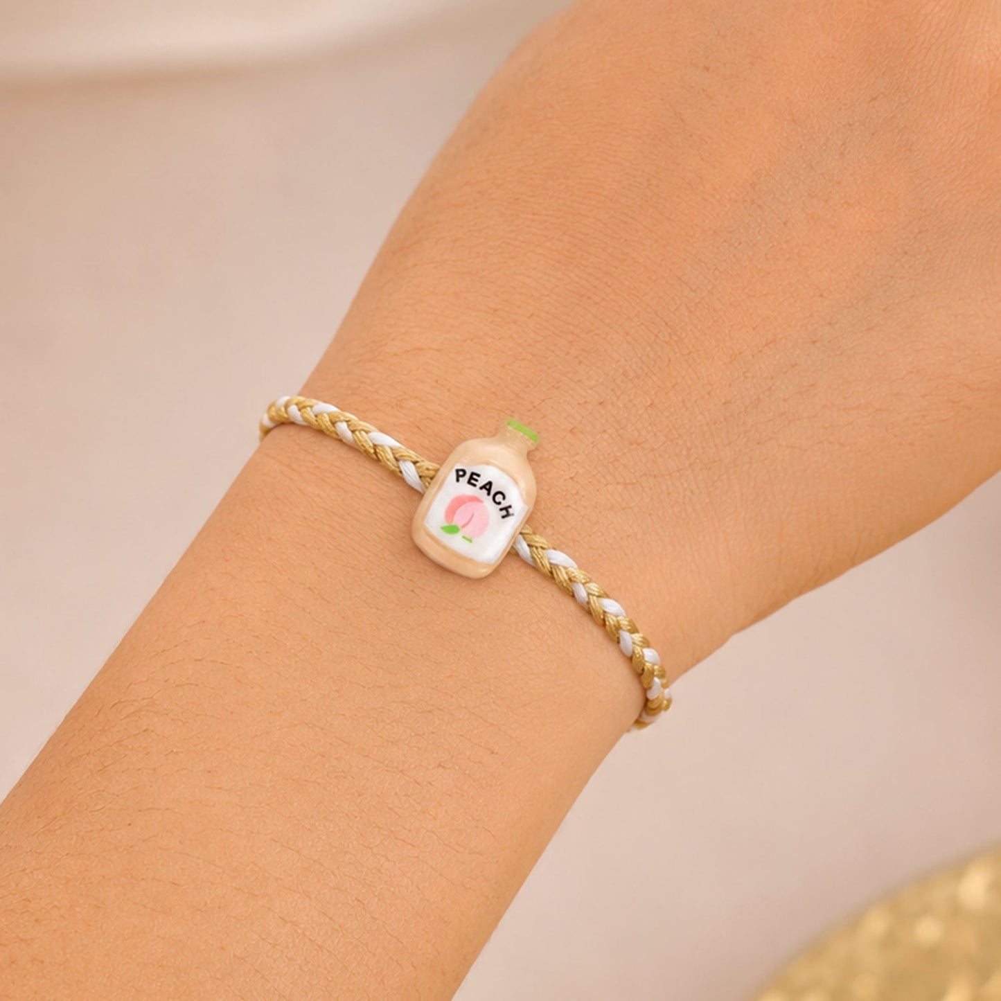 Fancy dori and charm detail of Peach Bottle Charm Rakhi