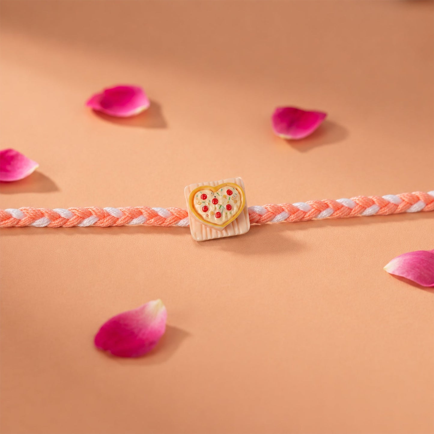 Side angle of fancy dori rakhi with heart pizza charm