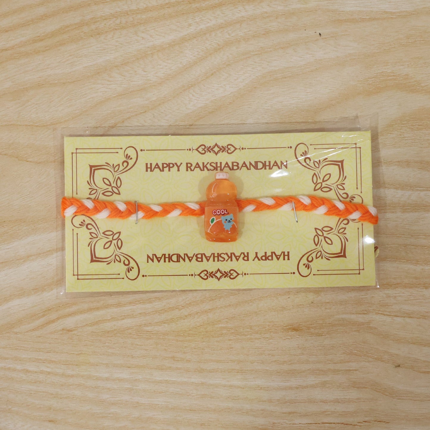 Fancy drink bottle charm rakhi tied neatly on white surface