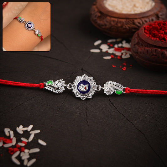 Silver round charm rakhi with red thread on white background