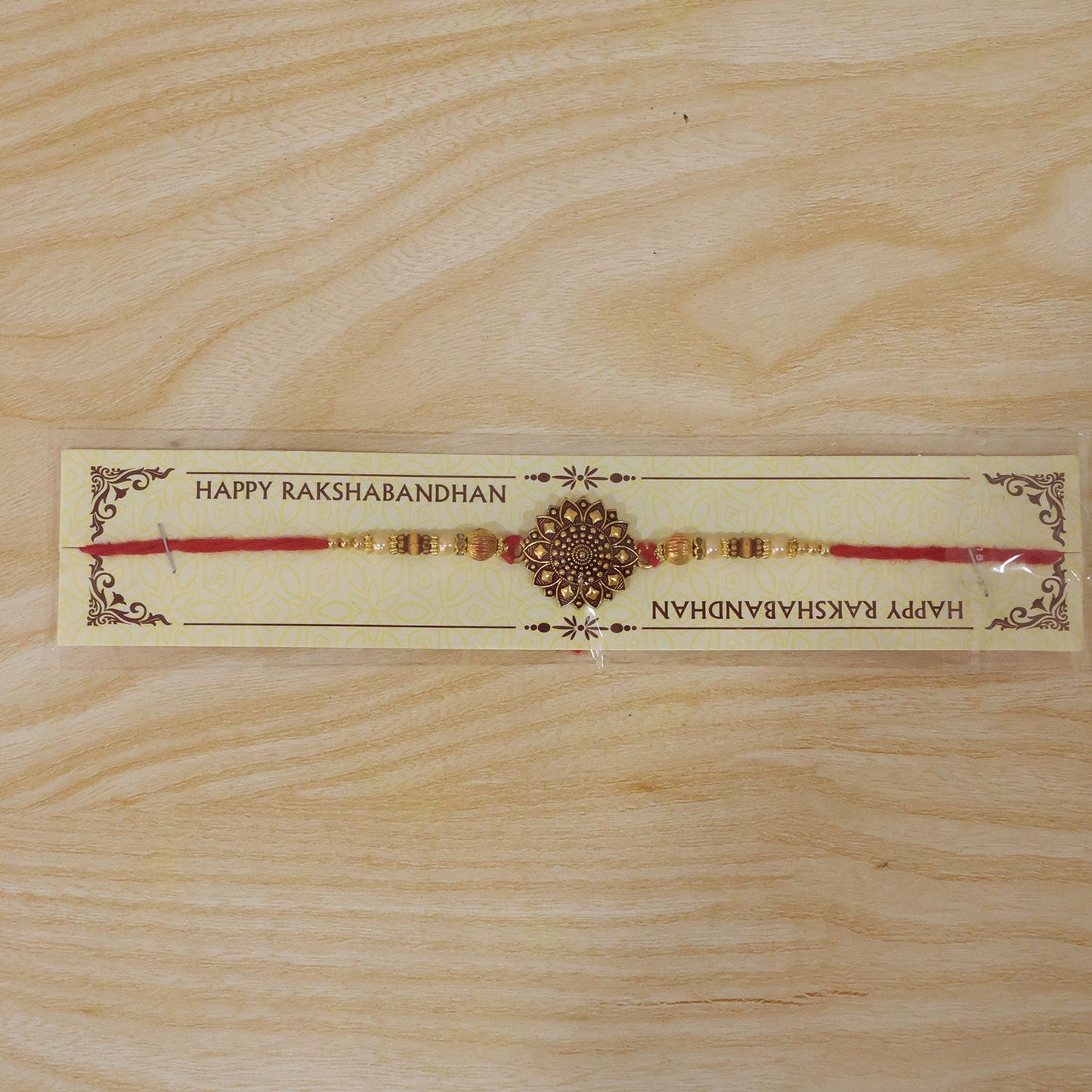 Top-down view of Antique Gold Floral Mandala Rakhi on white background