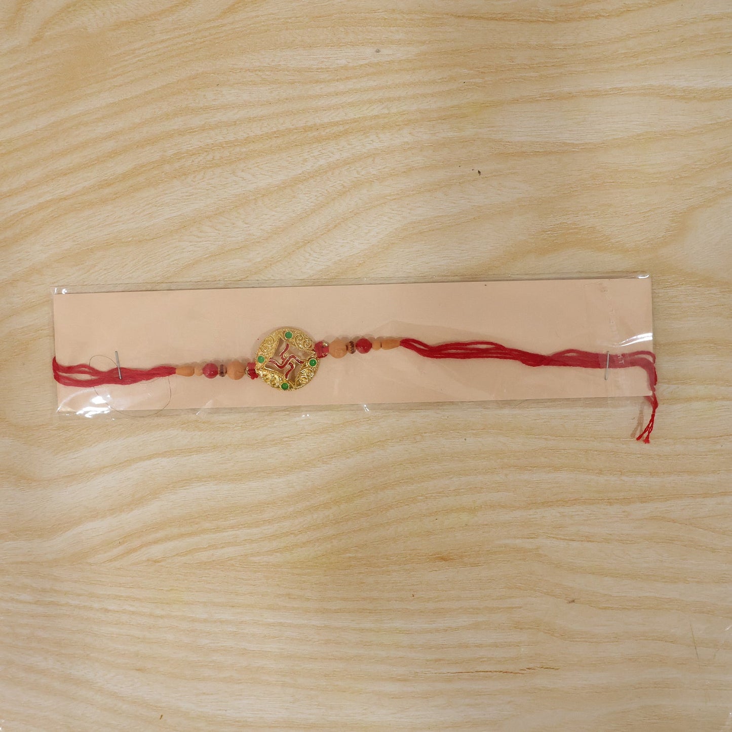 Auspicious Golden Swastik Rakhi with Wooden & Red Beads for Brother