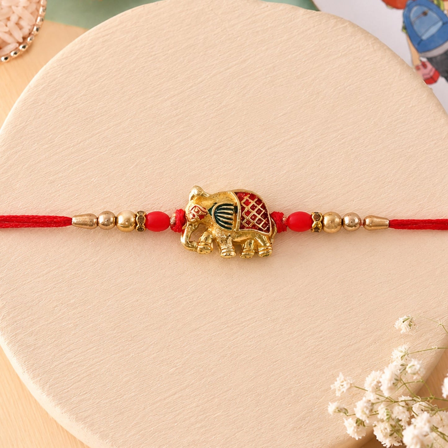 Detailed View of Gold Elephant Charm and Beads on Rakhi