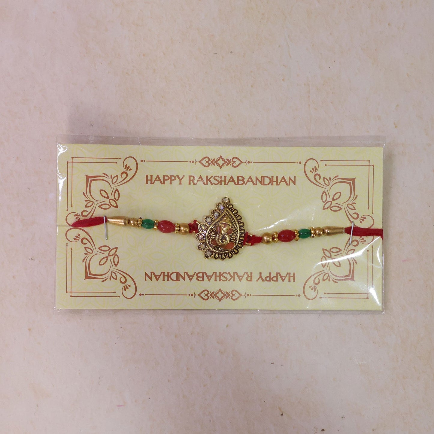 Antique Golden Ganesha Rakhi with Red & Green Beads and Crystals