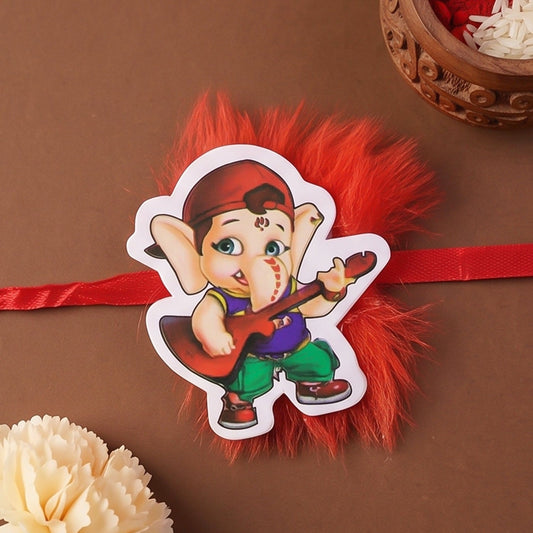 Ganesha character kids designer rakhi with a red and gold thread, shown on a white background.