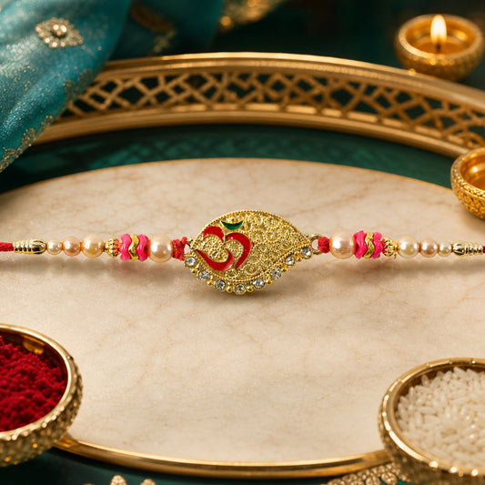 A gold paisley-shaped Om stone with red and green accents, flanked by pearls and pink beads on a red thread, rests on a gold